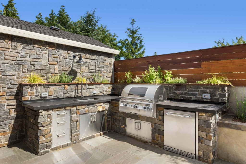 stone and stainless steel ourdoor kitchen on a patio